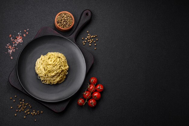 Foto pasta capellini o fideos con salsa pesto, sal y especias sobre un fondo de hormigón oscuro