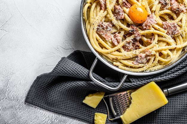 Pasta Carbonara, Bucatini in der Pfanne. Grauer Hintergrund. Draufsicht. Speicherplatz kopieren