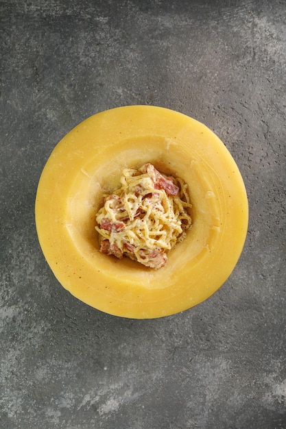 Foto pasta carbonara en la cabeza de queso sobre fondo de hormigón