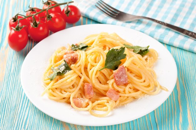 Pasta carbonara con jamón y queso sobre mesa de madera azul. Vista superior.