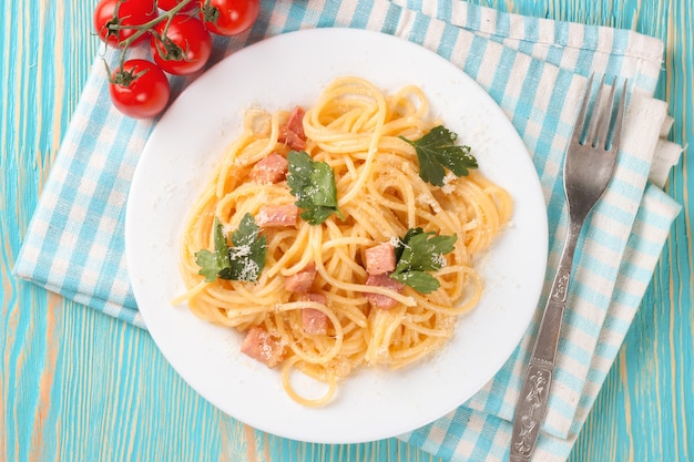 Pasta carbonara con jamón y queso sobre mesa de madera azul. Vista superior.