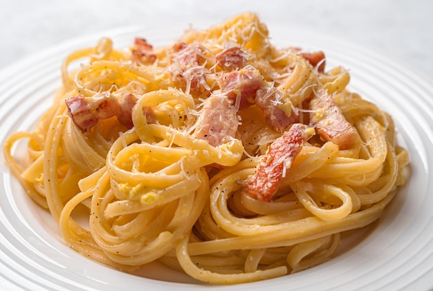 Foto pasta carbonara mit speck käsecreme und pfeffer nahaufnahme auf grauem hintergrund traditionelle italienische küche