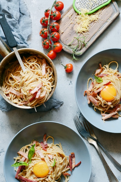 Pasta a la carbonara con tocino y parmesano en platos grises sobre la mesa