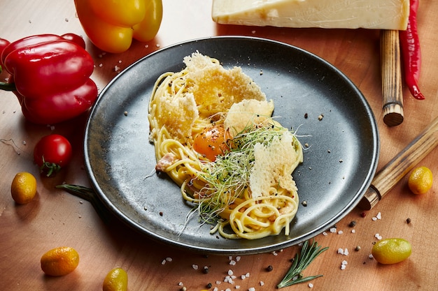 Foto pasta a la carbonara con yema y parmesano con salsa de crema. espagueti tradicional italiano para almorzar en superficie de madera