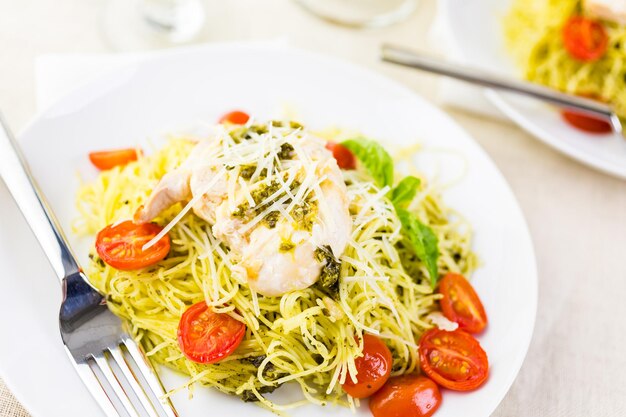 Pasta casera de cabello de ángel con salsa pesto, tomates cherry asados y pollo a la plancha.