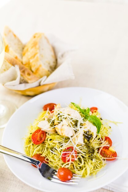 Pasta casera de cabello de ángel con salsa pesto, tomates cherry asados y pollo a la plancha.