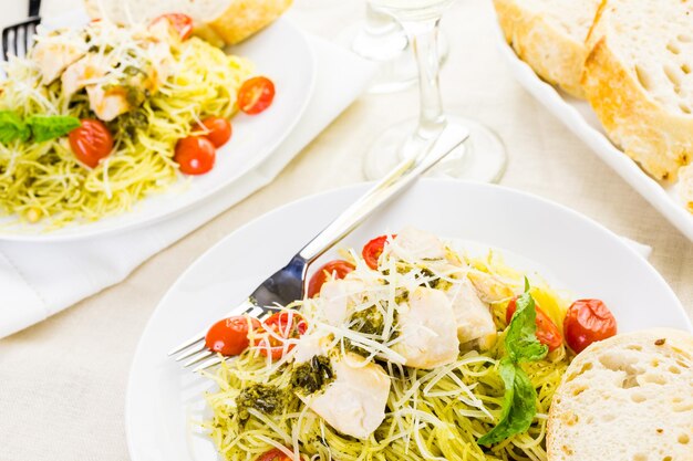 Pasta casera de cabello de ángel con salsa pesto, tomates cherry asados y pollo a la plancha.