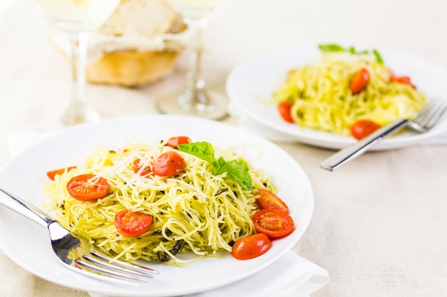 Pasta casera de cabello de ángel con salsa pesto y tomates cherry asados.