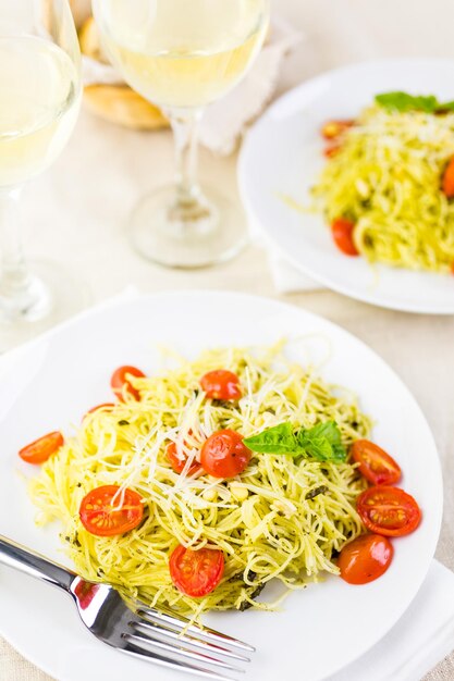 Pasta casera de cabello de ángel con salsa pesto y tomates cherry asados.