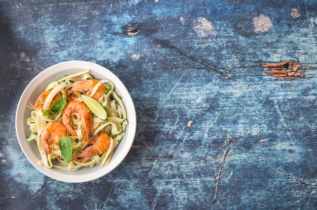 Pasta casera con camarones fritos y albahaca sobre mesa de madera rústica