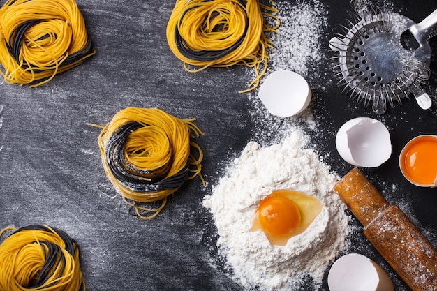 Pasta casera cruda e ingredientes sobre una superficie negra