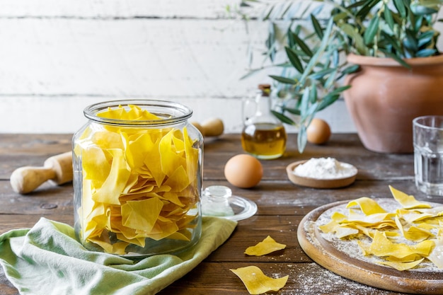 Pasta casera Maltagliati en tabla de cortar con ingredientes