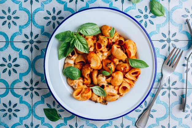 Pasta con champiñones salsa de tomate y albahaca sobre fondo de mosaico