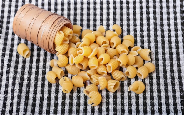 Foto pasta de chifferi rigati sin cocinar esparcida en toallas a cuadros negras grasa y alimentos no saludables