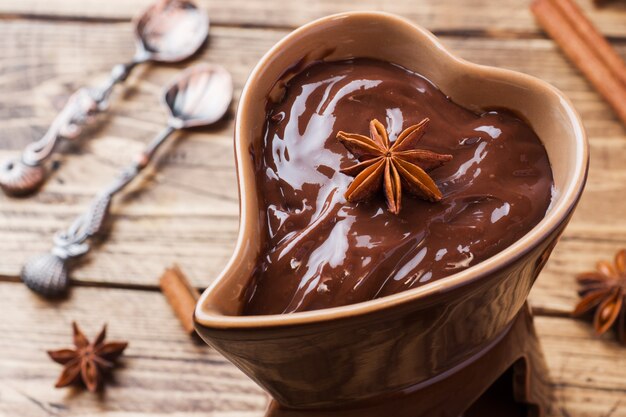 Pasta de chocolate con canela y anís. Fondue de chocolate sobre una mesa de madera. copia espacio