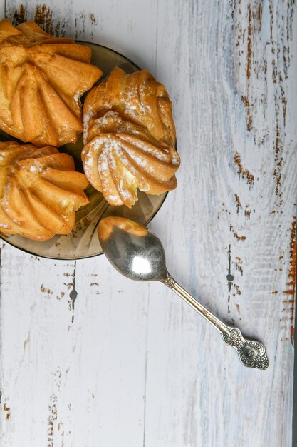 Foto pasta choux y cuchara, sobre fondo de madera. cierre la crema de choux. con una cuchara y tenedor de metal en el fondo