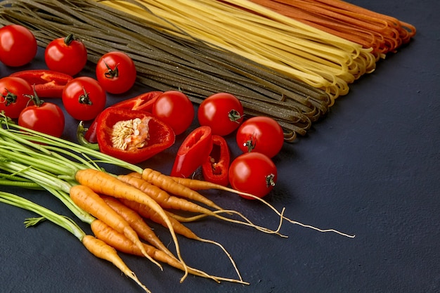 Pasta colorida casera con ingredientes naturales en una mesa de hormigón negro