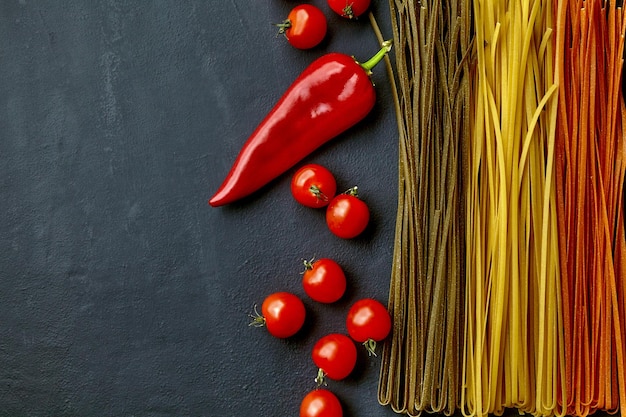 Pasta colorida casera con ingredientes naturales en una mesa de hormigón negro