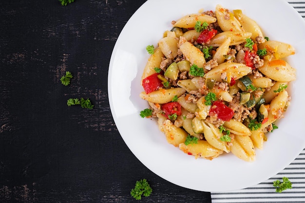 Pasta conchiglie. Conchas de pasta italiana con carne picada, calabacín, tomate y pimientos dulces. Vista superior, arriba