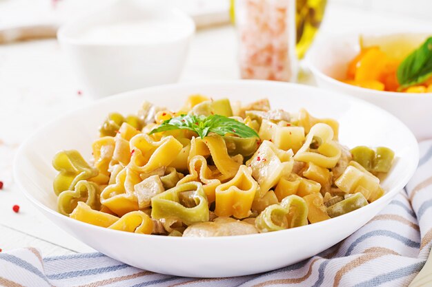 Pasta cremosa con pollo y berenjenas servida en un plato hondo. Comida italiana.