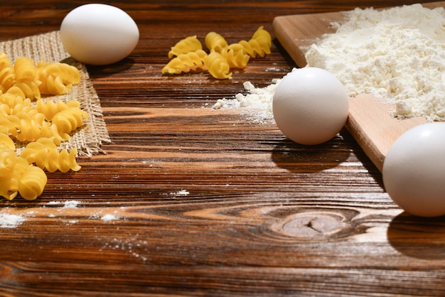 Pasta cruda e ingredientes para pasta sobre fondo de madera