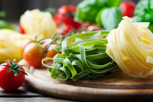 Pasta cruda, tomate y albahaca sobre la mesa de madera