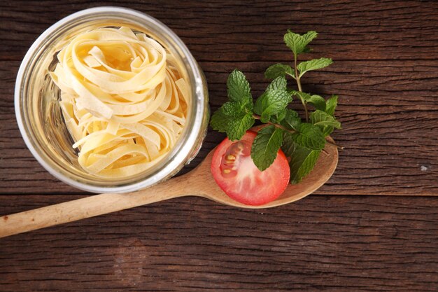 Foto pasta cruda y tomate en la mesa