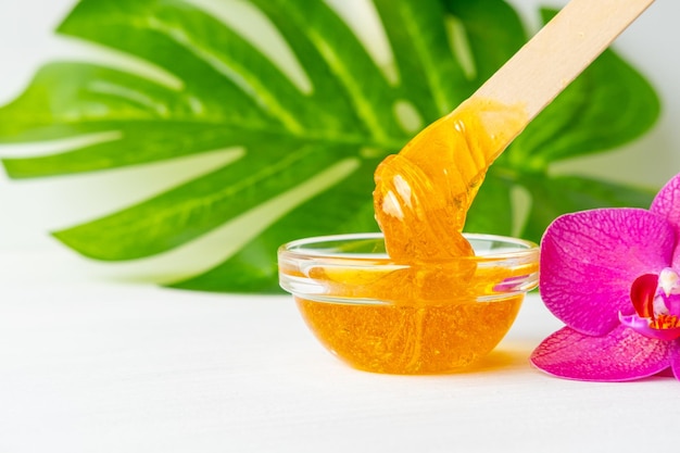 Pasta de açúcar ou cera mel para a remoção de cabelo flui da flor de espátula de madeira para cera