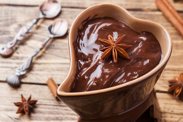 Pasta de chocolate com canela e anis. Fondue com chocolate em uma mesa de madeira. copie o espaço