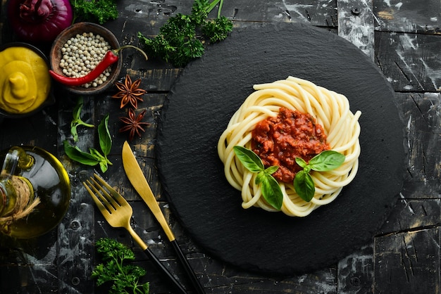 Pasta de espaguete com molho bolognese e manjericão em um prato de pedra preta comida italiana Vista superior Espaço livre para texto