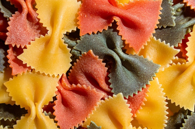 Foto pasta de farfalle colorida seca não cozida e macarrão cru em um fundo texturizado