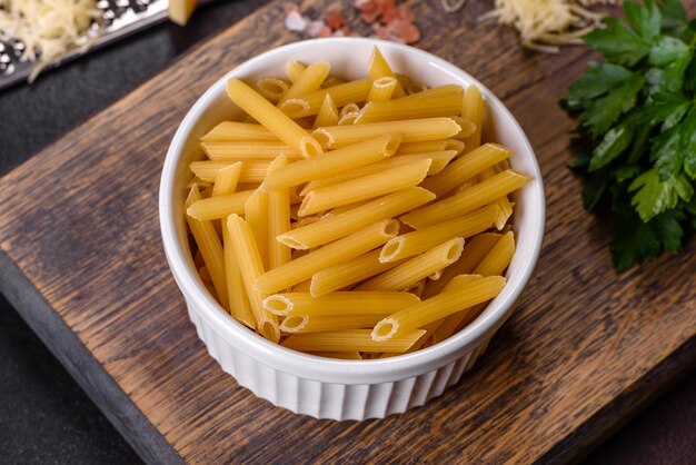 Pasta de tagliatelle crua com queijo ralado tomate cereja especiarias e ervas em uma tábua de madeira