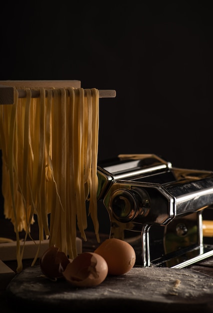 Foto pasta de tagliatelle preparada na hora é seca em um secador de madeira, cozinha italiana tradicional