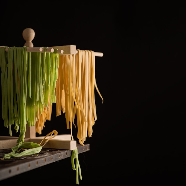 Foto pasta de tagliatelle preparada na hora é seca em um secador de madeira, cozinha italiana tradicional