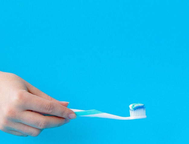 Pasta de dientes en primer plano de un cepillo de dientes en una luz azul.
