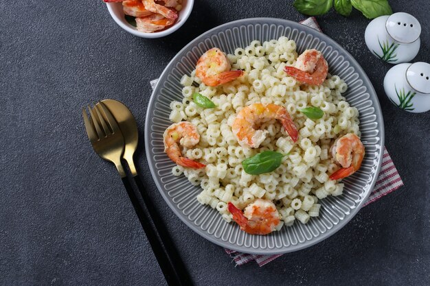 Pasta ditalini italiana con camarones y albahaca en placa gris sobre un fondo oscuro. De cerca. Vista desde arriba