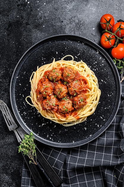 Pasta de espagueti con albóndigas y salsa de tomate. Cocina italiana. Fondo negro. Vista superior.