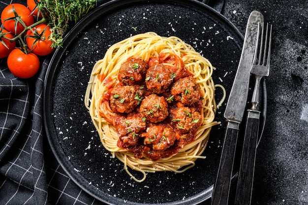 Pasta de espagueti con albóndigas y salsa de tomate. Cocina italiana. Fondo negro. Vista superior.