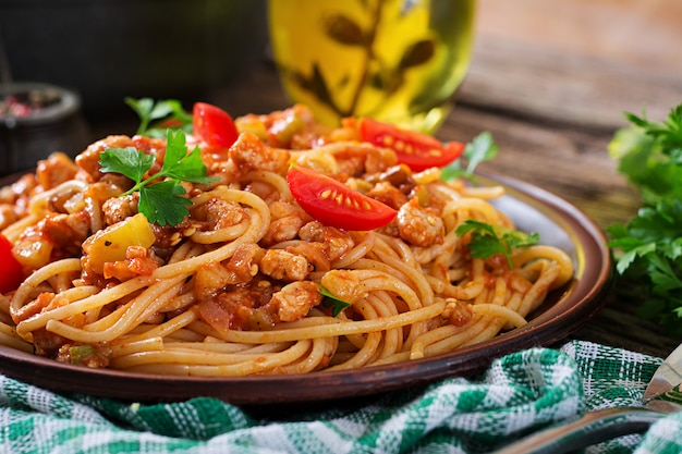 Pasta de espagueti a la boloñesa con salsa de tomate, verduras y carne picada - pasta italiana saludable casera sobre fondo de madera rústica.