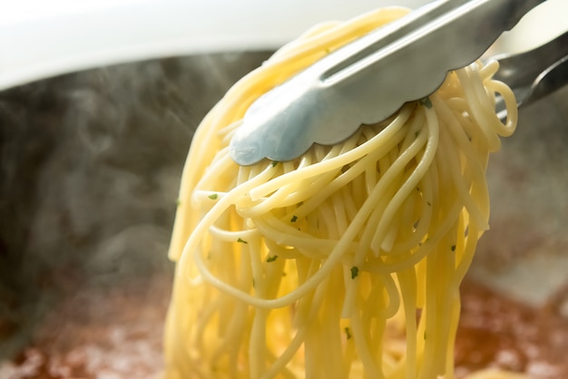 Pasta de espagueti cocida levantada por tong