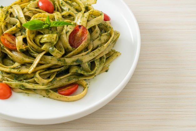 Pasta de espagueti fettuccine con salsa pesto y tomates estilo comida vegana y vegetariana