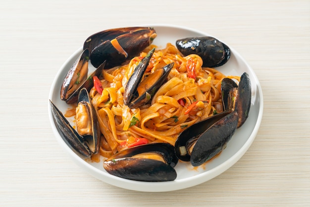 Pasta de espagueti con mejillones o almejas y salsa de tomate - estilo de comida italiana