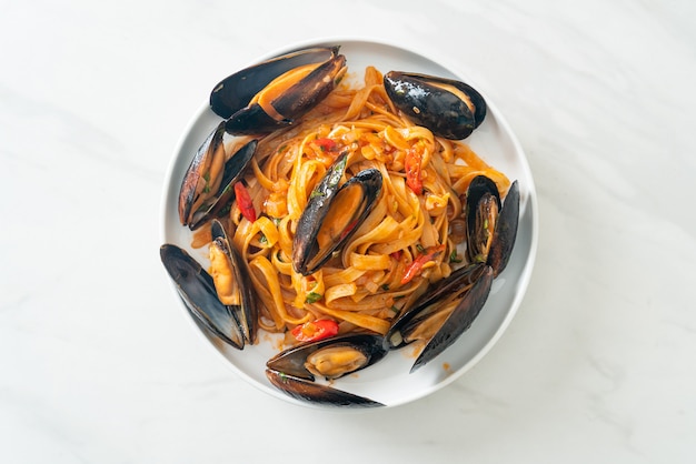 Pasta de espagueti con mejillones o almejas y salsa de tomate - estilo de comida italiana