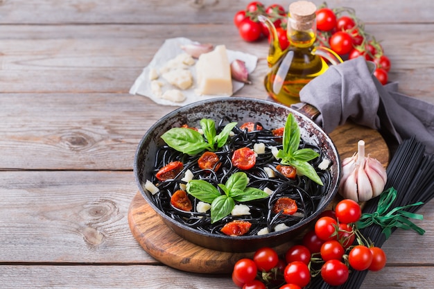 Pasta de espagueti negro con tomate, queso y albahaca