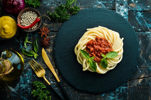 Pasta de espagueti con salsa boloñesa y albahaca en un plato de piedra negra Comida italiana Vista superior Espacio libre para texto