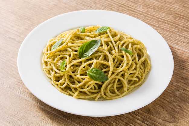 Pasta de espagueti con salsa de pesto en mesa de madera