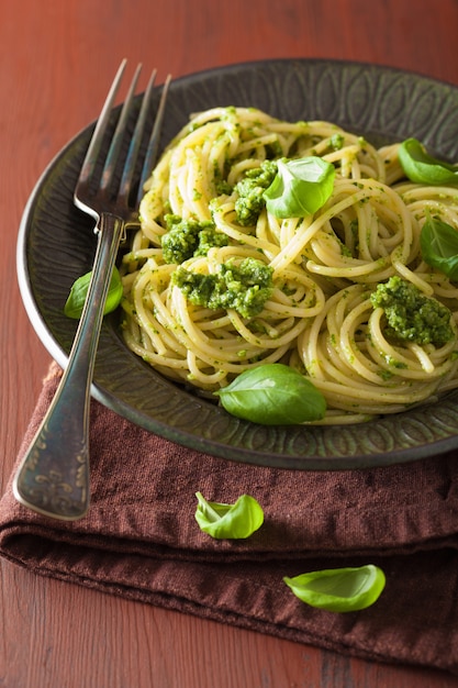 Pasta de espagueti con salsa de pesto sobre mesa rústica