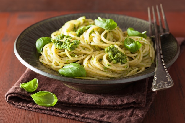 Pasta de espagueti con salsa de pesto sobre mesa rústica