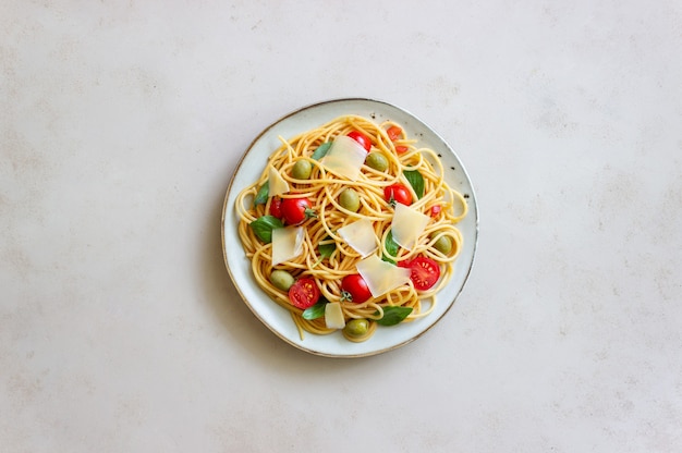 Pasta de espagueti con tomate, albahaca, aceitunas y queso parmesano. Alimentación saludable. Comida vegetariana.