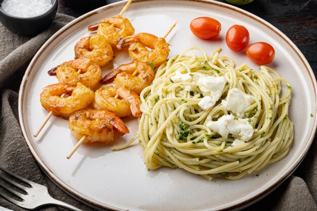 Pasta de espagueti Zuccini con pesto y parmesano y gambas, en un plato, sobre un fondo antiguo de madera oscura